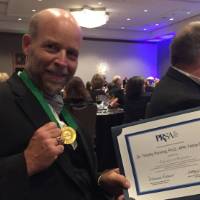 Tim Penning holds up his award certificate from PRSA